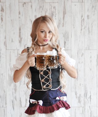 Elinde bira ile gülümseyen güzel kadın ahşap arka plan üzerinde poz. Oktoberfest konsepti.