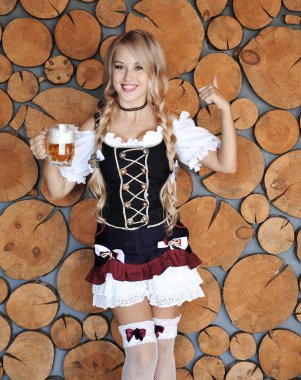 Elinde bira ile gülümseyen güzel kadın ahşap arka plan üzerinde poz. Oktoberfest konsepti.