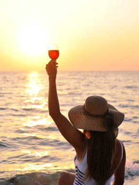  Yaz zamanı. Büyük şapkalı kadın, gün batımı kumsalında cam domuzlu..