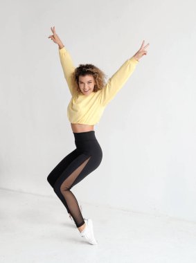 Dans stüdyosunda gülümseyen kıvırcık saçlı kadın.