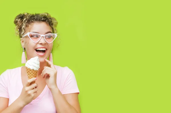 Young smiling woman with ice cream posing on green wall background