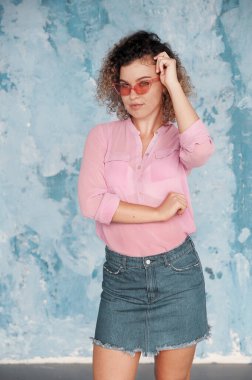 Güzel kıvırcık saçlı kadın arka planda poz veriyor.. 