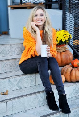 Turuncu kazaklı güzel kadın dışarıda kahve içiyor. 