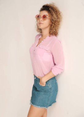 Güneş gözlüklü güzel, kıvırcık saçlı bir kadının evde eğlenirken çekilmiş otantik portresi.