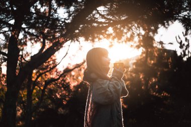 Küçük kız ormanda yürüyor ve sıcak çay içiyor..
