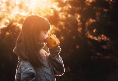 Küçük kız ormanda yürüyor ve sıcak çay içiyor..