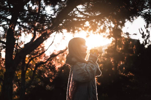 Küçük kız ormanda yürüyor ve sıcak çay içiyor..