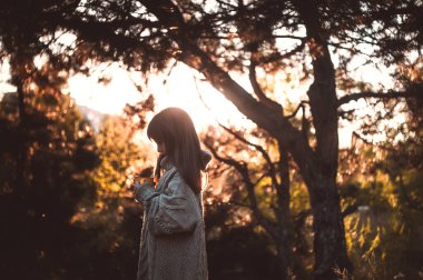 Ormanda gün batımında tatlı küçük kız çay içiyor..