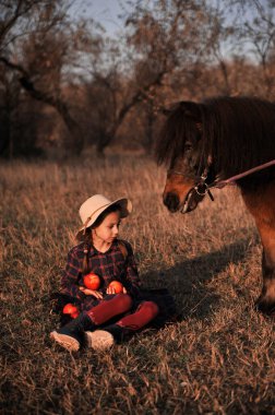 Küçük kız ormanda atla oynuyor..