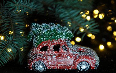 Kırmızı arka planda Noel oyuncağı ve çam ağacı ışıklarla.