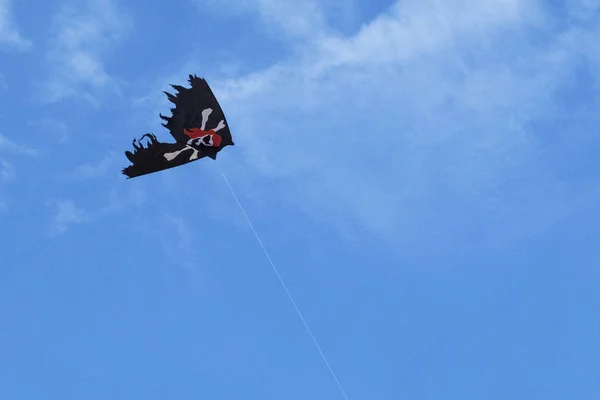 Bandera pirata cometa en el cielo azul con nubes blancas —  Fotos de Stock