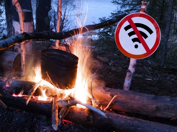 The no wifi sign near the fire and pot on the beach. digital detox concept and break from technology.