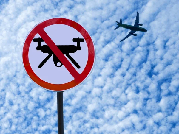 Schild verbietet Drohnen am Himmel mit Wolken und startendem Flugzeug. — Stockfoto
