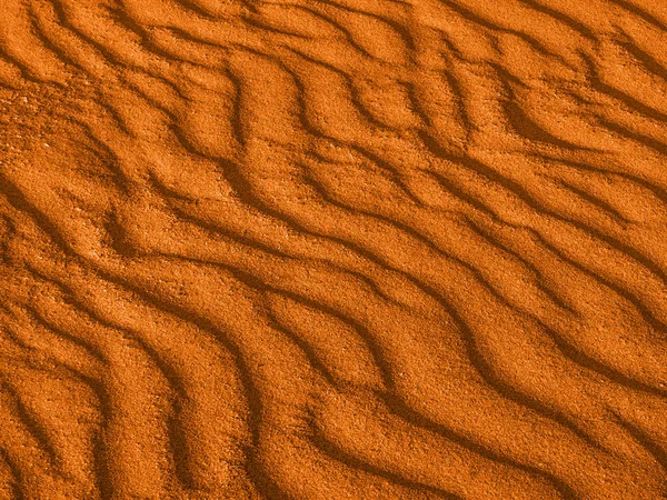 Textura de las olas amarillas de arena roja en la playa o en el desierto. las ondas de la arena son diagonales . — Foto de Stock