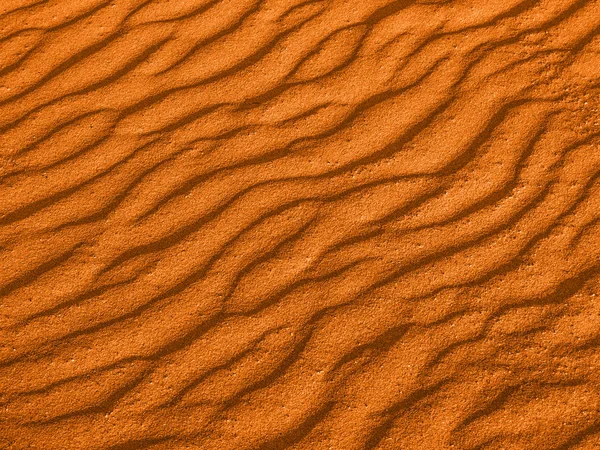 Textura de las olas amarillas de arena roja en la playa o en el desierto. las ondas de la arena son diagonales . — Foto de Stock