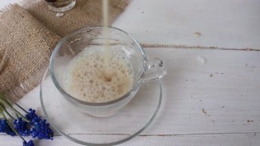 Kahve bir bardağa dökülür. Beyaz arka planda süt veya krema ile sıcak kahve