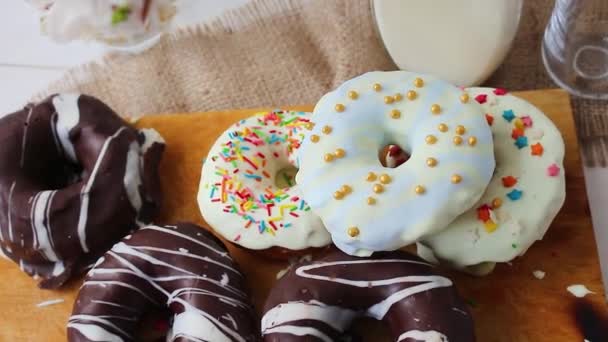 五颜六色的甜甜圈和巧克力 甜甜圈与牛奶 年轻人采取甜甜圈 — 图库视频影像