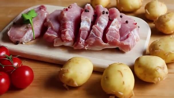 Bifes Porco Uma Tábua Madeira Batatas Novas Tomates Cereja Verdes — Vídeo de Stock