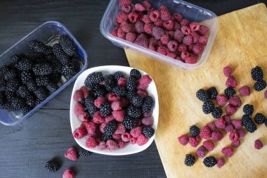 Ahşap bir arka plan üzerinde ahududu ve böğürtlen meyveleri. Kırmızı yırtık