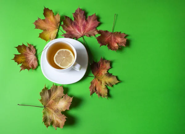 Autumn still life. Cup of tea with maple autumn leaves and inscr