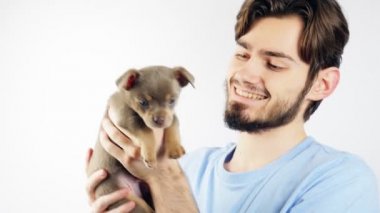 Sakallı bir adam kollarında bir Chihuahua köpeği tutuyor. Neşeli adam.
