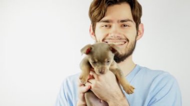 Sakallı bir adam kollarında bir Chihuahua köpeği tutuyor. Neşeli adam.