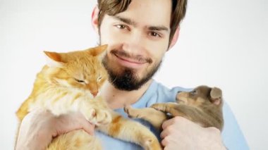 Sakallı bir adam kızıl bir kedi ve bir chihuahua köpeği tutuyor. Evcil hayvanlar. Adam mutlu.