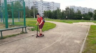 Ağır çekim. Çocuk bir futbol sahasına motosikletle geldi.