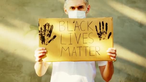 手に厚紙のポスターを手にした白髪の男が碑文を持つ Black Life Matter — ストック動画