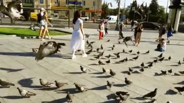 07 / 31 / 2020. Ukrayna. Harkiv. Beyaz elbiseli bir kız merdivenlerden iniyor. Etrafta bir sürü güvercin var. Kız ve güvercinler. Fotoğraf çekimi devam ediyor. Yavaş çekim