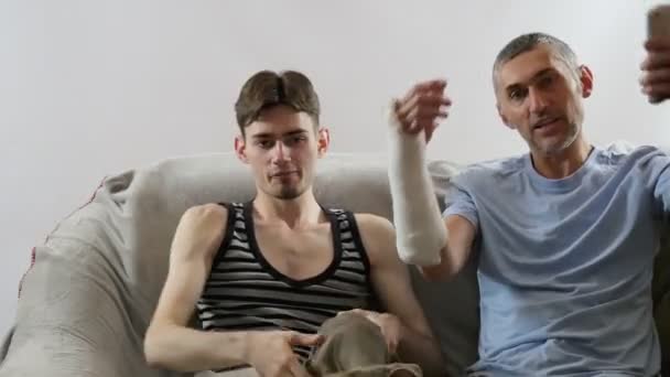 Männer Schauen Fern Ein Mann Mit Gips Arm Sportspiel Fußball — Stockvideo