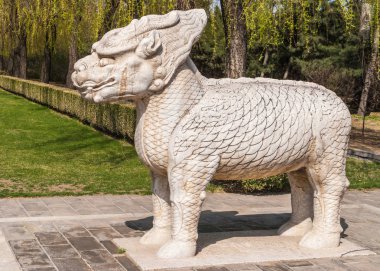 Beijing, Çin - 28 Nisan 2010: Ming Hanedanı mezarlar etki alanı veya Ming Changling. Beyaz-kahverengi ayakta bir aslan heykeli closeup. Ağaçlar arkada ve ışık mavi gökyüzü.