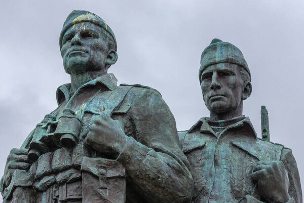 Lochander, Scotland - June 11, 2012: Closeup of two soldier heads at green-gray bronze Commando Memorial statue along A82 and near Spean River under cloudy sky. 