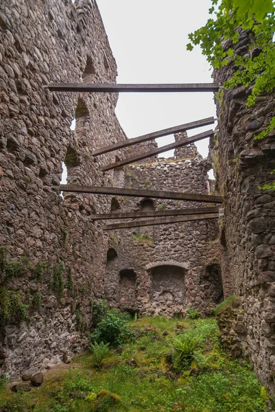 Invergarry, İskoçya - 11 Haziran 2012: Uzun boylu koyu duvarlar onları Invergarry kalede desteklemek için ahşap Çıtçıt ile içinde harap kahverengi. Yabani ot alanı fethetti. Gri gökyüzü.