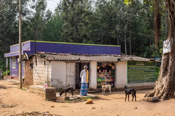 Belathur 卡纳卡 2013年11月1日 店主站在简陋的杂货店前 与狗和山羊在石头上建造 坚固的房子和绿色的森林背景 前褐色污垢 — 图库照片