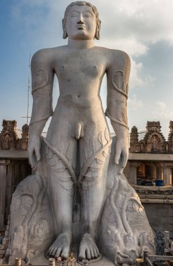 Shravanabelagola, Karnataka, Hindistan - 1 Kasım 2013: Jain Tirth granit dev Bhagwan Bahubali heykel gri. Tapınak inşa ve gökyüzü arka tarafta. Gün batımı karanlık gökyüzü.