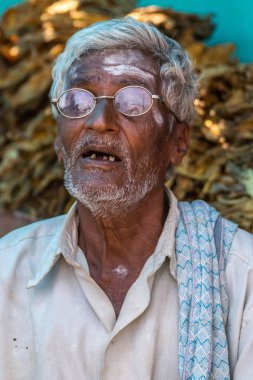 Nilavagilukaval, Karnataka, Hindistan - 1 Kasım 2013: Closeup eski kötü kahverengi dişler gösterilen açık ağız ile adam ağaran. Dairesel gözlük ve kirli beyaz gömlek giyer.