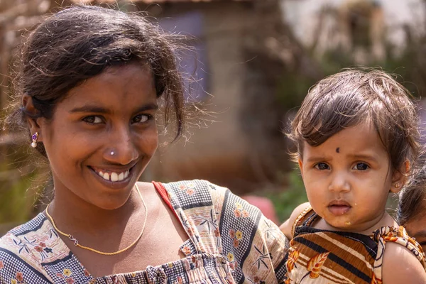 腕に赤ん坊の娘の笑みを浮かべて暗い髪若い母親の Nilavagilukaval カルナタカ インド 2013 クローズ アップ両方の金の宝石類 色あせたブラウン バック グラウンド — ストック写真