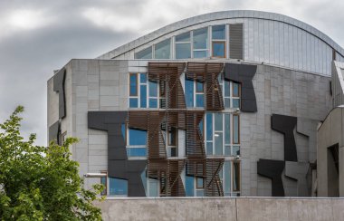 Edinburgh, İskoçya, İngiltere - 12 Haziran 2012: Bulutlu karanlık gökyüzü altında İskoç Parlamentosu ön cephe bölümünün Modern mimari. 