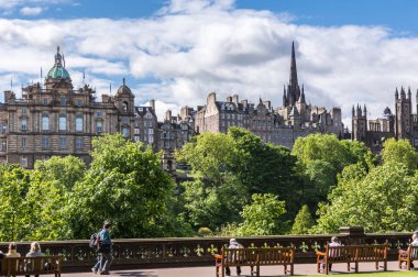 Edinburgh, İskoçya, İngiltere - 13 Haziran 2012: Scott Monument to Market Street Lloyd Bankacılık grubu ve Edinburgh Üniversitesi kuleleri ile arıyorum. Yeşil yapraklar, insanlar Park. Mavi gökyüzü beyaz bulutlar ile.