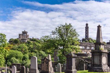 Edinburgh, İskoçya, İngiltere - 13 Haziran 2012: Calton Hill önemli eserlere mavi bulutlu gökyüzü altında arka planda ile eski Calton mezarlığında yeşil bitki örtüsü arasında kahverengi mezar taşlarının satırları ayarla.