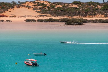 Broome, Wa, Avustralya - 29 Kasım 2009: Kırmızı dunes üstte kırmızı Buck koyu yeşil bazı bitki düşük tide masmavi su için arka plan olarak. Üç küçük zevk tekneler, bir beyaz bir çizgi çekerek.