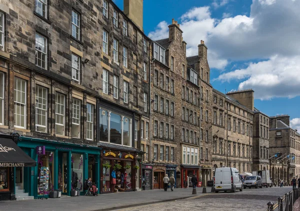 Edinburgh, İskoçya, İngiltere - 14 Haziran 2012; Streç turistik dükkanlar Royal Mile boyunca 4-5 hikayeler yüksek kahverengi binalar tarihi kümesinde. İnsanlar ve araba ile sokak sahne. Mavi gökyüzü, beyaz bulutlar.