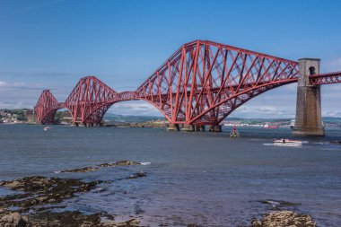 Queensferry, İskoçya, İngiltere - 14 Haziran 2012: Kırmızı portre metal ikonik Forth köprü mavi gökyüzü ve masmavi bir deniz arasında Firth of Forth üzerinden tren için.