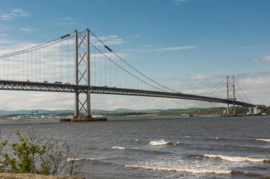Queensferry, İskoçya, İngiltere - 14 Haziran 2012: İleri yol asma köprü üzerinde Firth of Forth mavi gökyüzü ve gri su arasında. Ufukta yeşil tepeler.