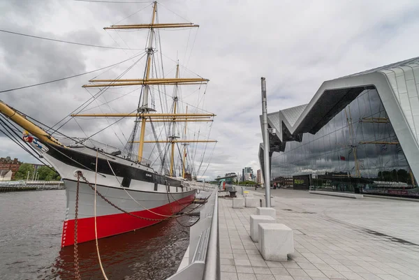 Glasgow, İskoçya, İngiltere - 17 Haziran 2012: Boyunca River Clyde, Riverside Mueum bina ve uzun gemi önünde ağır gri cennet altında yuvalanmış.