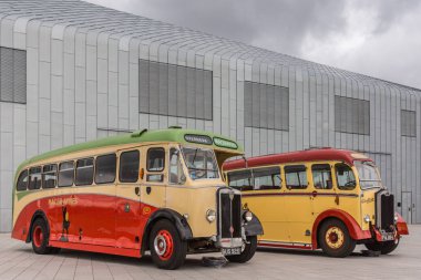 Glasgow, İskoçya, İngiltere - 17 Haziran 2012: Boyunca River Clyde, dış Riverside Müzesi, vintage sarı ve kırmızı batı ve Macbraynes halk otobüsleri ağır cennet altında.