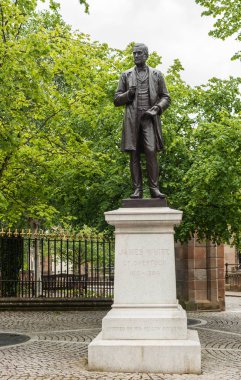 Glasgow, İskoçya, İngiltere - 17 Haziran, 2012:James beyaz bronz heykelin Katedrali dışında gri taş kaide üzerine. Siyah gri gökyüzü karşı şekil. Çevresinde yeşil yeşillik.