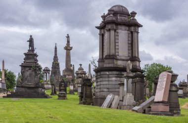 Glasgow, İskoçya, İngiltere - 17 Haziran 2012: Nekropolis. Grup uzun ve kısa Anıtı kahverengi taş anıtlar ile John Knox dikilitaş ağır cennet altında kalıp. Yeşil çimen