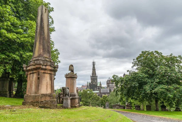 Glasgow, İskoçya, İngiltere - 17 Haziran 2012: Nekropolis. Kahverengi taş anıtlar ve yeşil park gibi olan ortamda spire Katedrali'nin arka tarafta cennet altında mezar taşları.